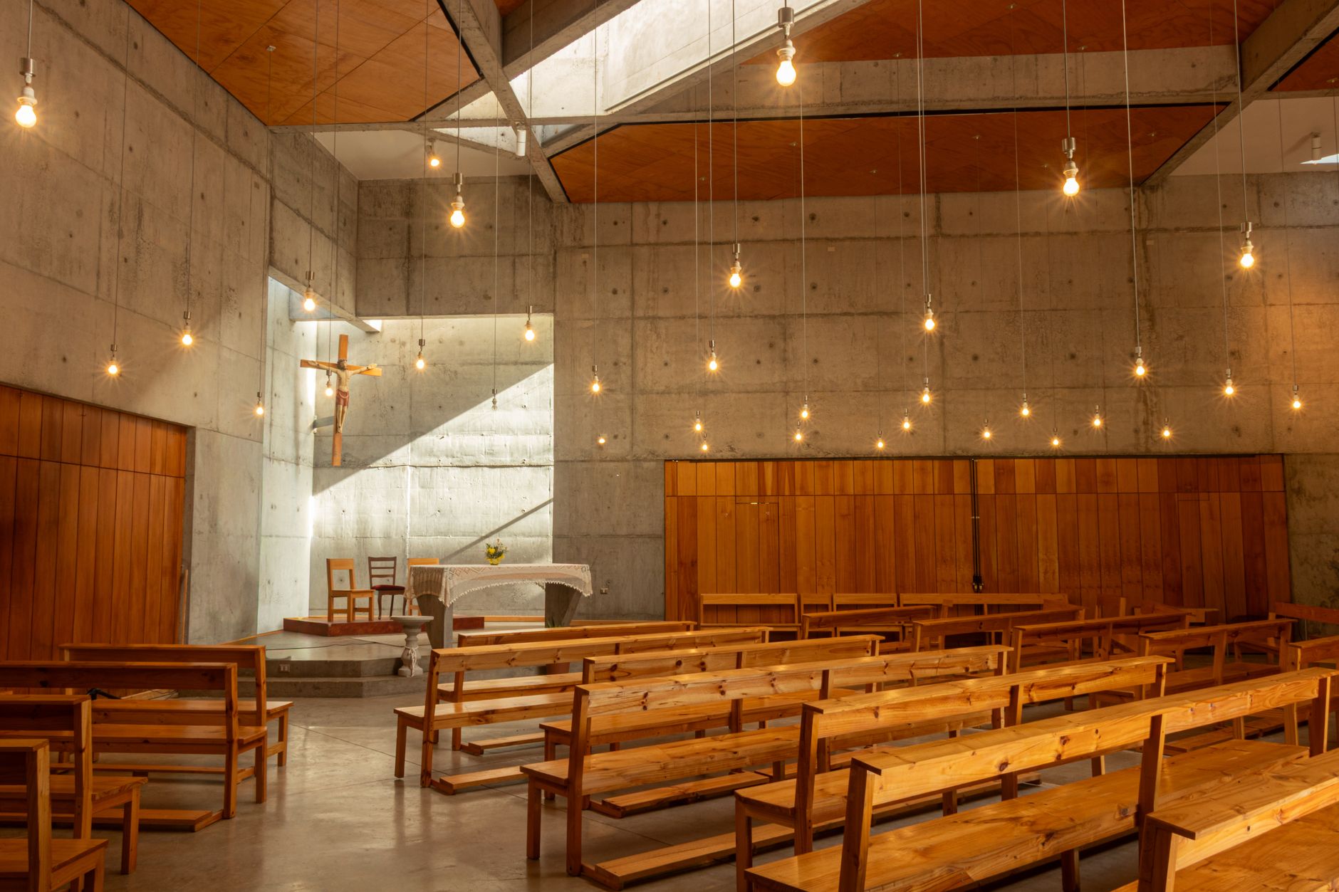 Warmly lit modern church interior with wooden benches